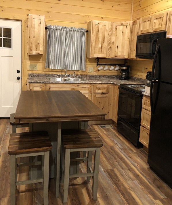 Enjoy casual dining and gatherings in this cozy kitchen with a central table and benches, wooden cabinetry, and a stainless steel sink.