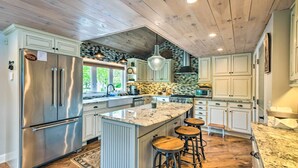 A spacious kitchen with a large island, stainless steel appliances, and wooden bar stools. - Stunning Enfield Home w/ Deck & Boat Dock! (Enfield)