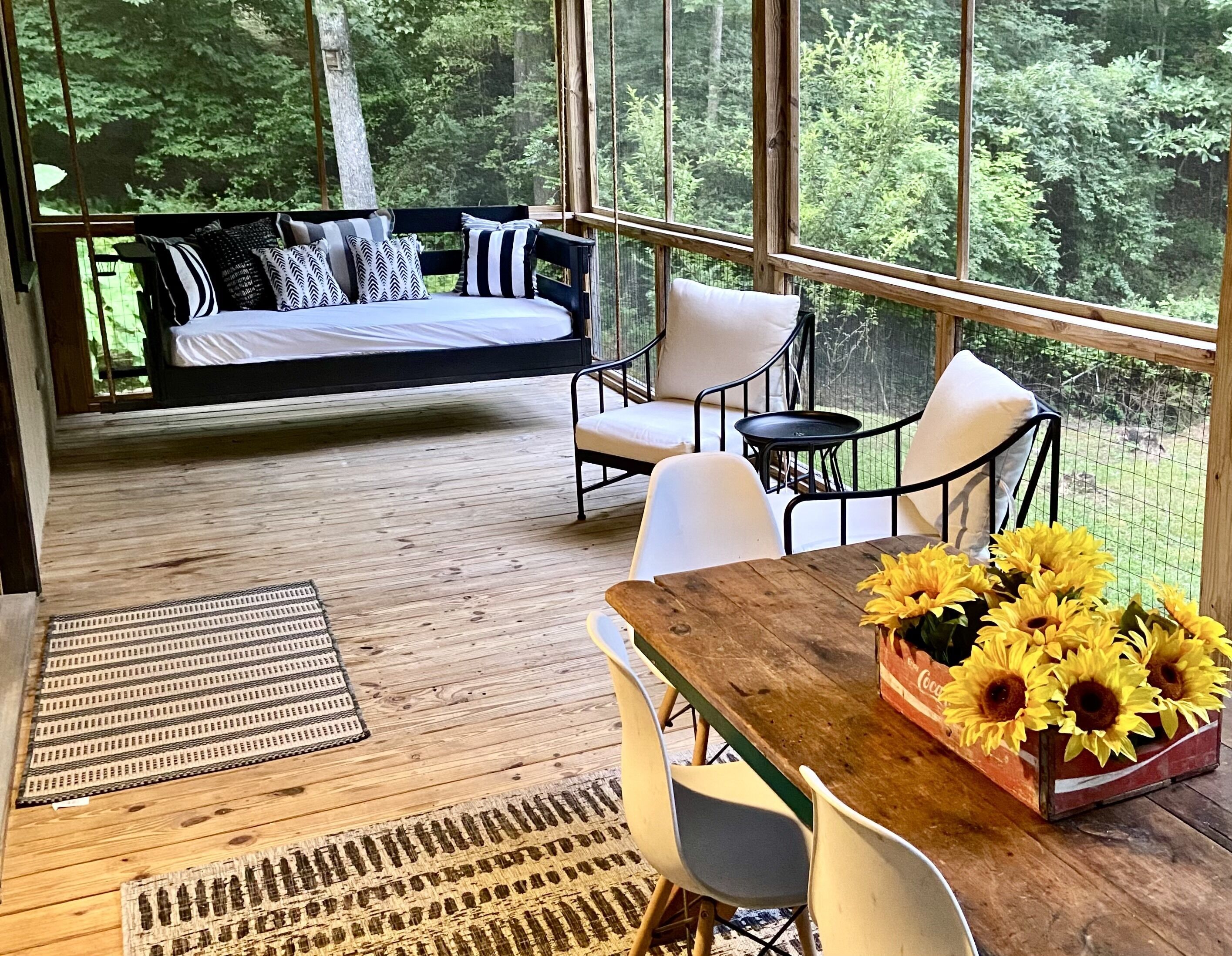 Une pièce confortable avec un lit, un coin salon et une table décorée de tournesols.