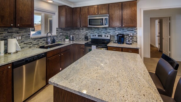 A modern kitchen with dark wood cabinets, stainless steel appliances, and a granite countertop. - Sunflower On the Lake (Lake Havasu City)