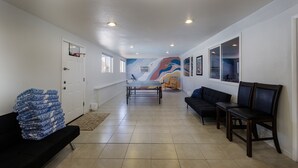 A hallway with a basketball hoop, a couch, a bench, and a colorful mural on the wall. - Sunflower On the Lake (Lake Havasu City)