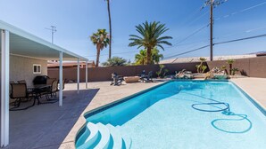 A swimming pool with a built-in slide, surrounded by palm trees and a covered patio area with outdoor furniture. - Sunflower On the Lake (Lake Havasu City)