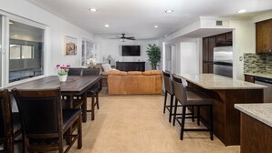 A modern kitchen with a dining area, wooden furniture, and a flat-screen TV on the wall. - Sunflower On the Lake (Lake Havasu City)