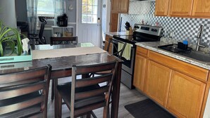A kitchen with wooden cabinets, a stainless steel sink, and a tiled backsplash. - Walk to Beach  2BR Near Dining & Shopping (Rocky Point)