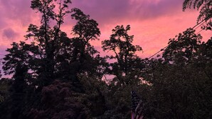 A sunset with pink clouds, trees, and an American flag. - Walk to Beach  2BR Near Dining & Shopping (Rocky Point)