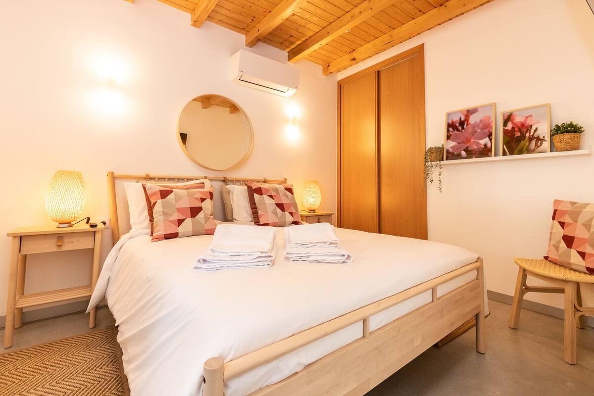 A neatly made bed with pillows, a bedside lamp, and a mirror on the wall.