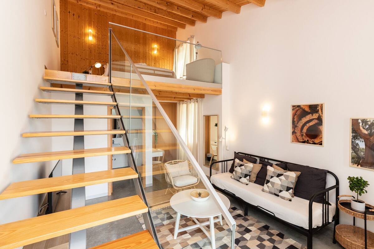 A modern interior with a staircase, a sofa, and a dining area.