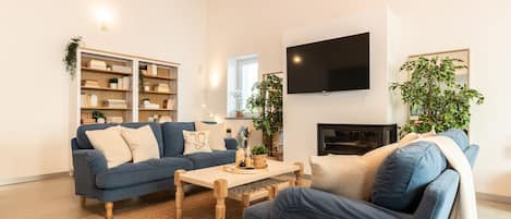 A modern living room with a blue sofa, a wooden coffee table, and a bookshelf.