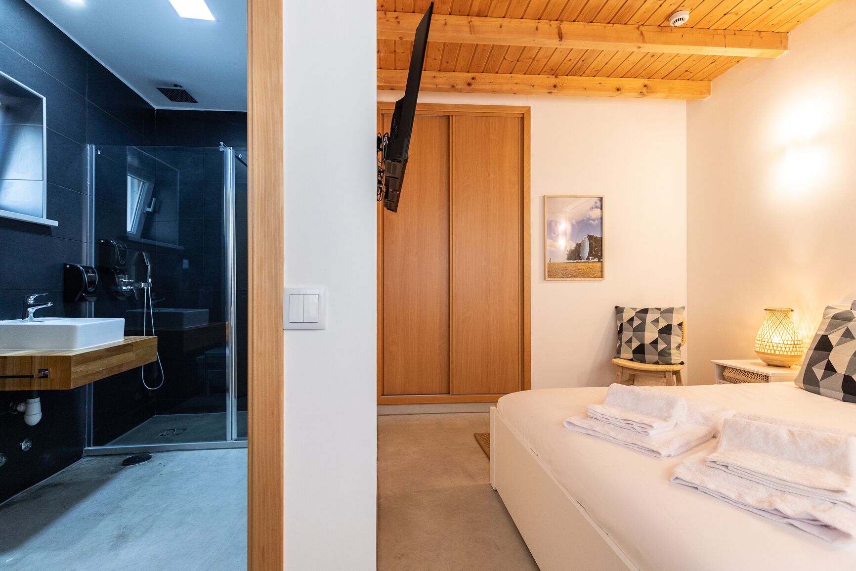 A modern bathroom with a glass shower enclosure, a wooden vanity, and a white sink.