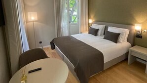 A hotel room with a bed, bedside tables, a round table, and a chair. - Pier House Accommodation (Funchal)
