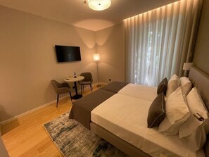 A hotel room with a bed, a desk, a chair, a TV, and a window with curtains. - Pier House Accommodation (Funchal)