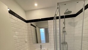 A modern bathroom with a glass-enclosed shower, a white sink, and a checkered floor. - Pier House Accommodation (Funchal)
