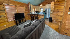 Interno di una baita di legno con un soggiorno, una cucina e una sala da pranzo.
