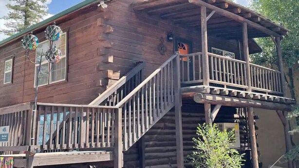 Un rustico chalet in legno con un balcone e un piccolo portico.