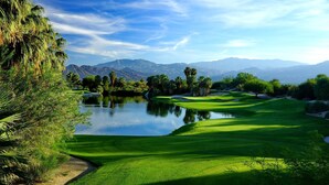 A golf course with a pond, palm trees, and mountains in the background. - Westin Desert Willow Resort (Palm Desert)