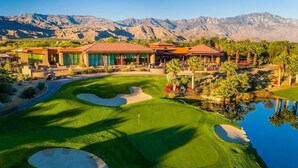 A golf course with a clubhouse, palm trees, and mountains in the background. - Westin Desert Willow Resort (Palm Desert)