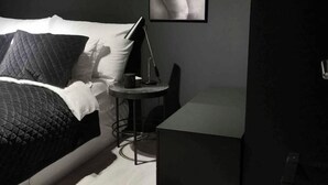 Une chambre moderne avec un lit, une table de chevet et un tableau accroché au mur.