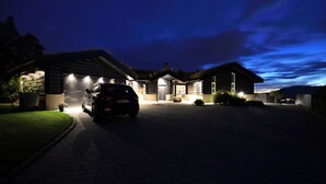 Une maison moderne avec une voiture garée dans l’allée, de nuit.