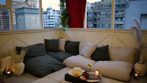 Un coin salon accueillant avec un canapé d’angle, une petite table avec des bougies et une vue sur la ville grâce à de grandes fenêtres.
