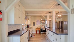 A modern kitchen with wooden cabinets, a central island, and pendant lighting. - Peaceful Lake House - Brand New Remodel (Macy)