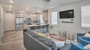 A modern kitchen with white cabinets, a stainless steel refrigerator, and a bar area with stools. - Gorgeous Greeley Getaway - Close to Parks! (Greeley)