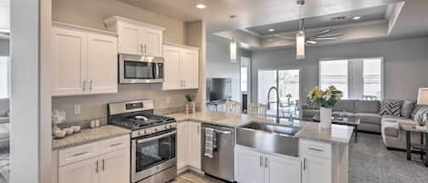 Una cocina moderna con armarios blancos, electrodomésticos de acero inoxidable y una isla central.