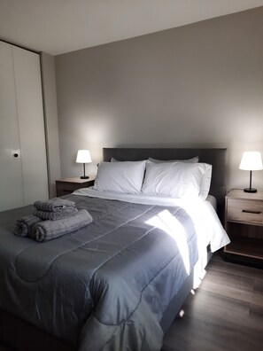 Relax in comfort with a large bed, dark headboard, and soft bedside lamps.