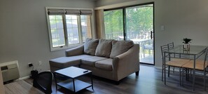 Relax in this spacious living area with a sofa, side table, and dining table, offering a view of the outdoors.
