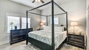 A four-poster bed with a dark frame, a bedside table with a lamp, and a dresser with drawers. - ~ 1 Mi to Pier & Beaches! Family Home in Galveston (Galveston)