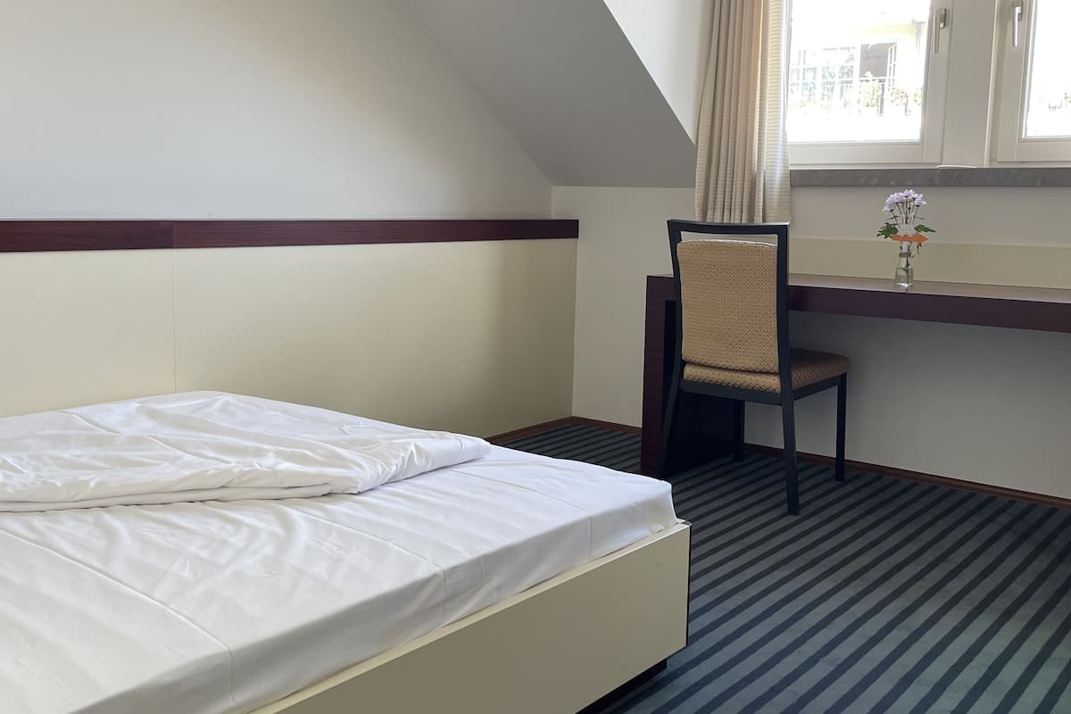 A hotel room with a bed, a desk, and a chair.