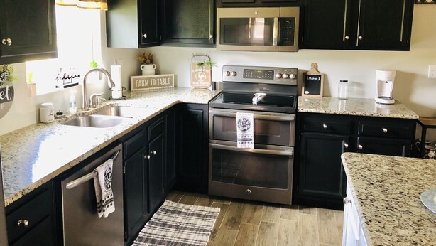 A kitchen with dark cabinets, stainless steel appliances, a granite countertop, and a farmhouse sign. - Cheerful 4-Bedroom In Beautiful Dandridge  (Dandridge)