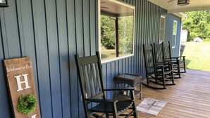 A porch with a 'Welcome to Our Home' sign, a wicker chair, and a wooden bench. - Cheerful 4-Bedroom In Beautiful Dandridge  (Dandridge)