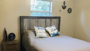 A bedroom with a wooden bed, a nightstand, a clock, and a window. - Cheerful 4-Bedroom In Beautiful Dandridge  (Dandridge)