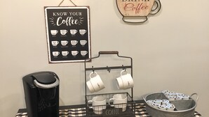 A coffee station with a coffee maker, mugs, and a tray of coffee pods on a checkered table. - Cheerful 4-Bedroom In Beautiful Dandridge  (Dandridge)