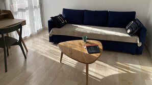 Un salon avec un canapé bleu, une table basse en bois et une table à manger avec des chaises.