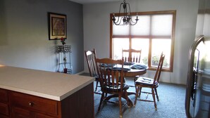 A kitchen with a dining table, chairs, a chandelier, and a refrigerator. - 3 br country home close to town with hot tub (Muncie)