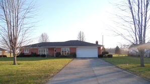 A single-story house with a garage, a front lawn, and leafless trees. - 3 br country home close to town with hot tub (Muncie)
