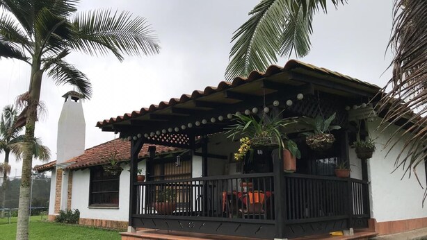 A house with a porch, a white exterior, and a tiled roof.