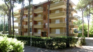 A multi-story apartment building with balconies, surrounded by trees and greenery.