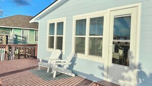 Een huis in een lichtblauwe kleur met witte details en grote ramen.
