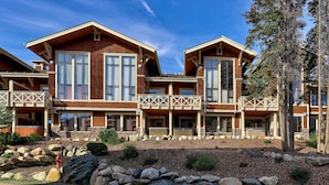 A two-story building with a balcony, large windows, and a stone foundation. - Spacious 3bdrm Family Retreat Ski in/out w/hot tub (Sun Peaks)