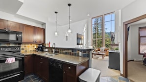A modern kitchen with dark wood cabinets, a granite countertop, and a stainless steel sink. - Spacious 3bdrm Family Retreat Ski in/out w/hot tub (Sun Peaks)