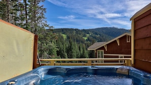 A hot tub with a view of a forested mountain range. - Spacious 3bdrm Family Retreat Ski in/out w/hot tub (Sun Peaks)