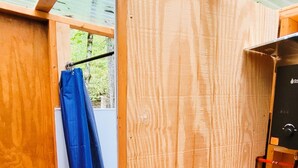 Een houten kamer met een metalen dak, een blauw gordijn en een gele tafel.