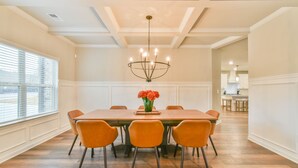 Un comedor con una mesa de madera, seis sillas anaranjadas y un candelabro.