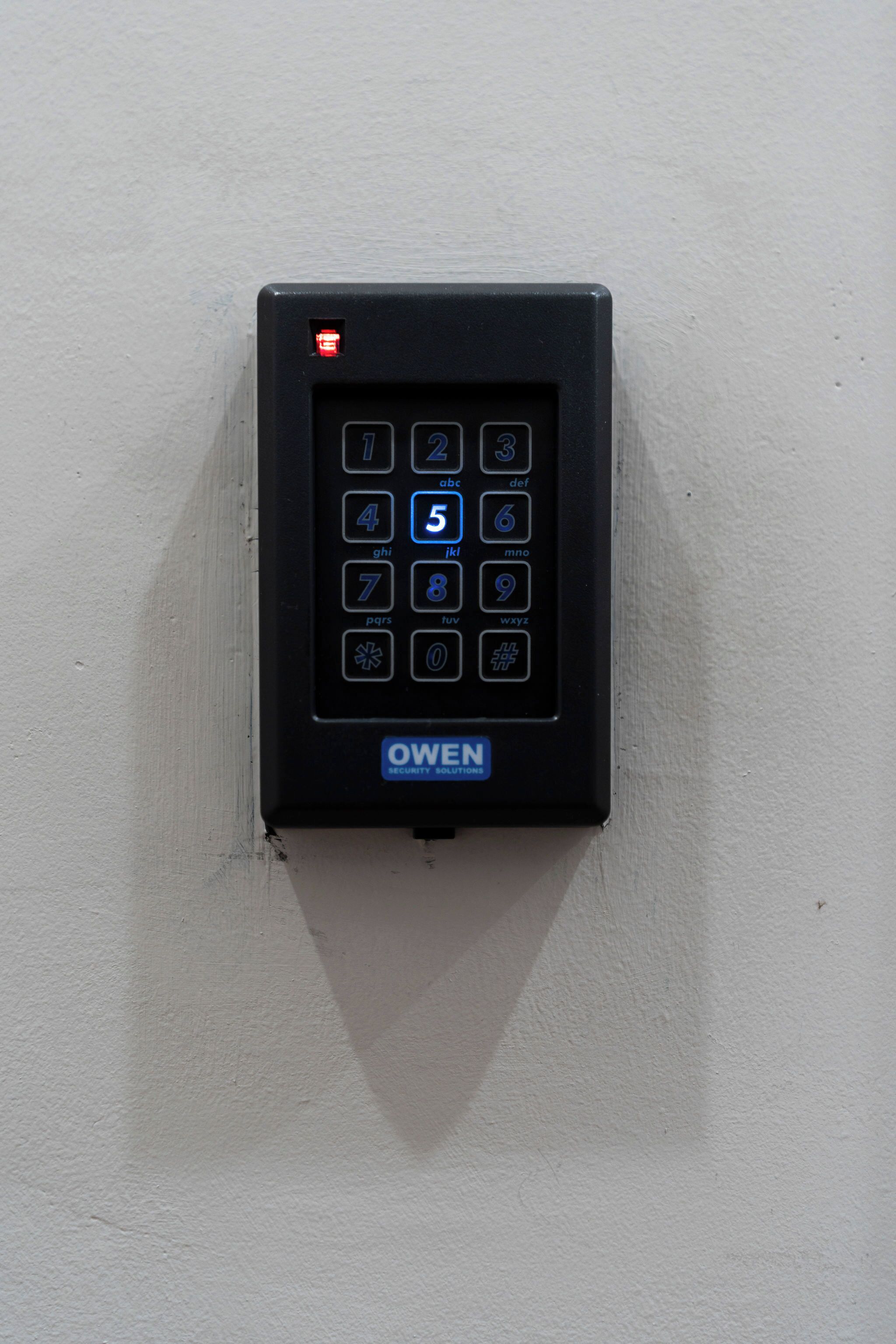 Een keypad met de merknaam 'OWEN' op een witte muur.