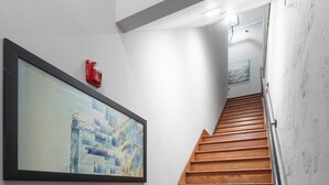 A wooden staircase with a handrail, a framed artwork on the wall, and a security camera. - Soho Loft 5 (Cartersville)