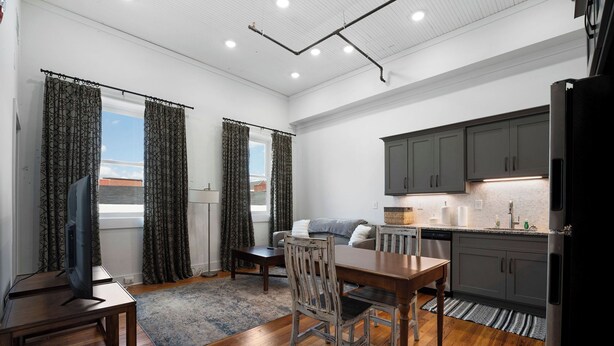 A compact living space with a dining area, kitchen, and a large window with curtains. - Soho Loft 5 (Cartersville)