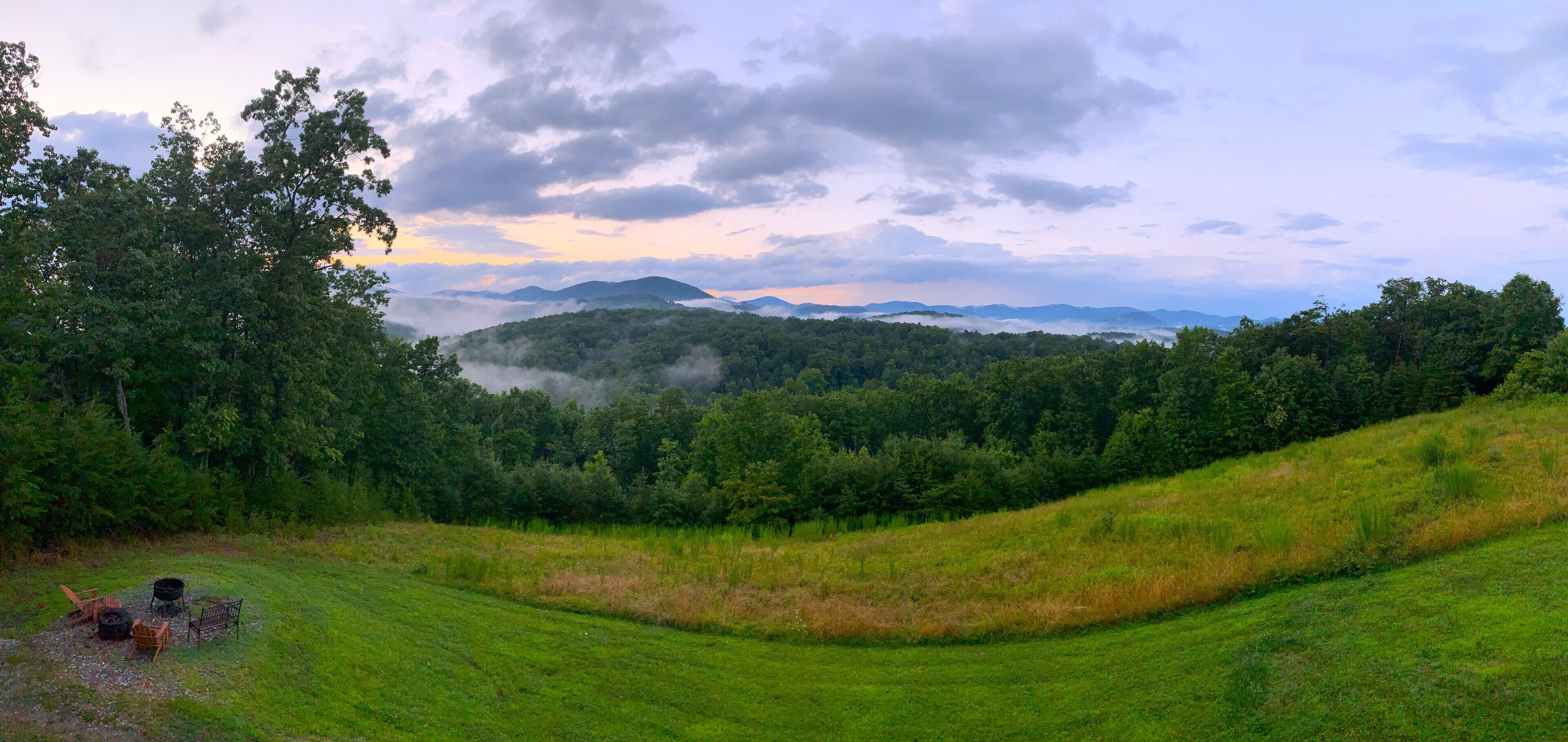 A lush green landscape with rolling hills and a forested area.