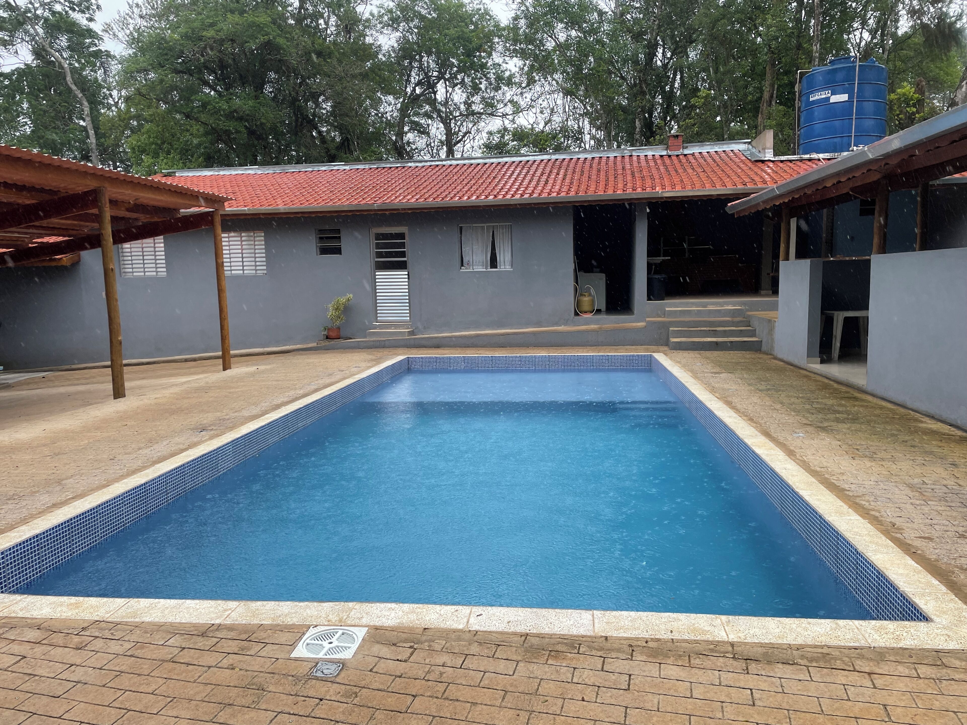 A rectangular swimming pool with a tiled edge, surrounded by a brick patio.